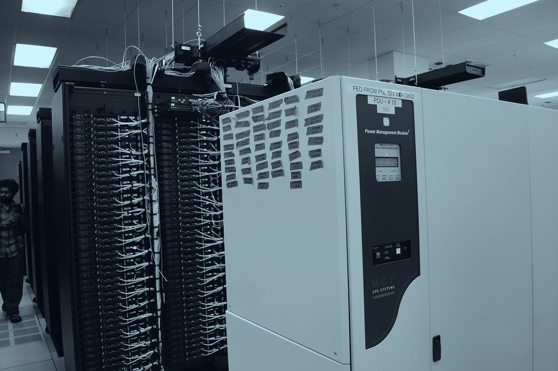Baies de serveurs et câblage réseau dans une salle de production informatique.